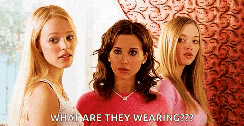 three women are standing next to each other and one of them is wearing a pink shirt .