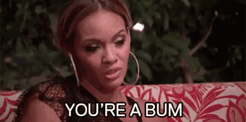 a woman is sitting on a couch talking to another woman and saying `` you 're a bum '' .