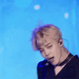 a young man with a microphone in his mouth is dancing on a stage .