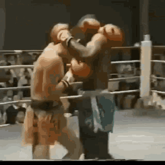two boxers are fighting in a boxing ring and one of them is wearing a green shorts