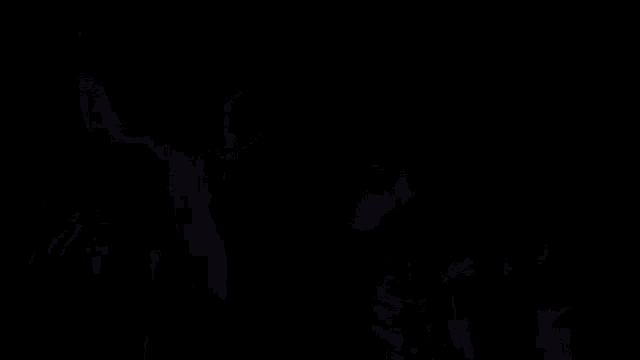 a man in a hooded jacket is standing in front of a group of people .