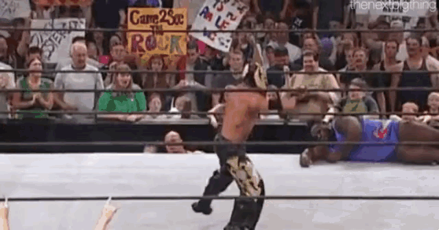 a wrestling match is taking place in front of a crowd .