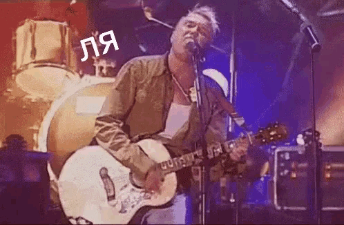 a man is playing a guitar and singing into a microphone on stage .