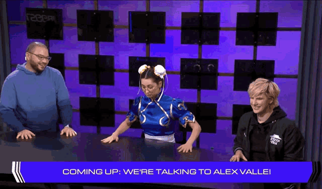 three people are sitting at a table with the words coming up we 're talking to alex valle on the screen