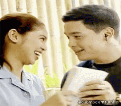a man and a woman are looking at each other and smiling while holding a piece of paper .