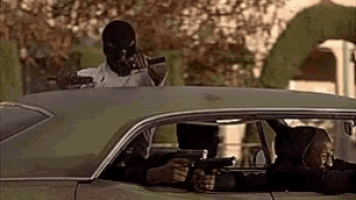 a man in a mask is holding a gun while sitting in a car with other people .