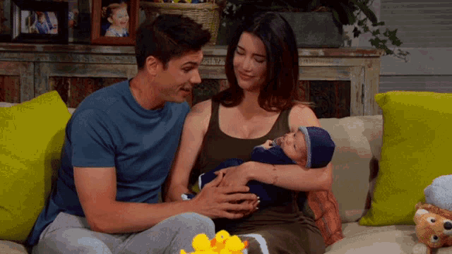 a man and a woman sitting on a couch holding a baby