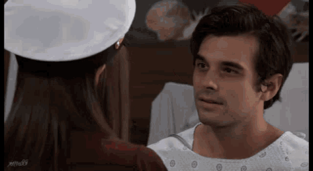a man in a hospital gown is looking at a woman in a nurse 's hat