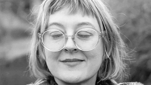 a black and white photo of a woman wearing glasses with her eyes closed