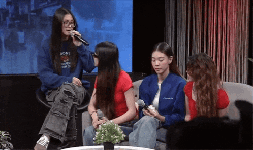a girl wearing a sony sweatshirt is singing into a microphone while three other girls watch