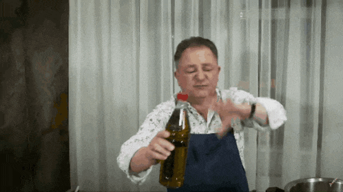 a man in a blue apron is holding a bottle of coke
