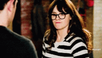 a woman wearing glasses is looking at a man wearing a black and white striped shirt .