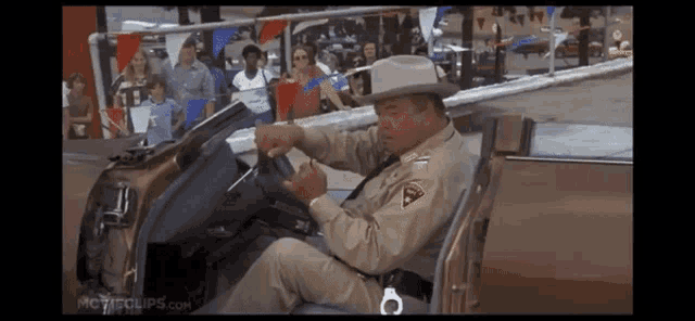 a man in a cowboy hat is sitting in a car with movieclips.com written on the bottom