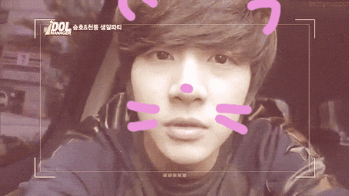 a young man with a cat face drawn on his face and the words idol manager behind him