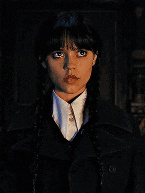 a woman with braids wearing a white shirt and black coat