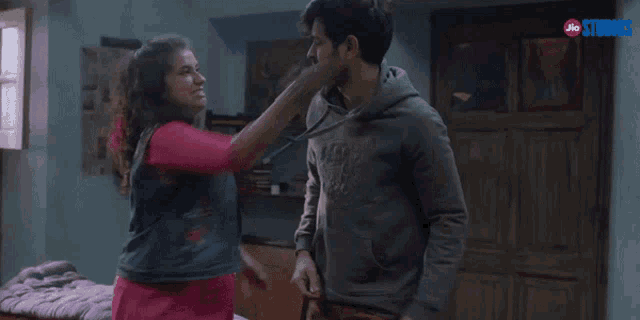a man and a woman are standing in a room with jio studios written on the bottom