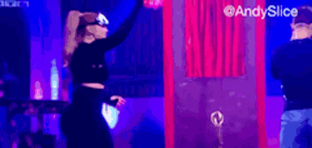 a woman wearing a virtual reality headset stands in front of a red curtain with the words andy slice on it