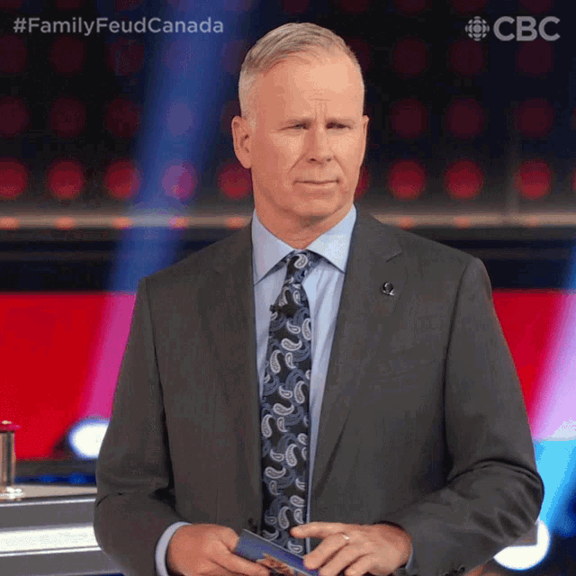 a man in a suit and tie is standing in front of a cbs sign