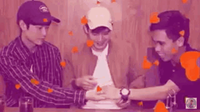three men are sitting at a table with their hands on a table .