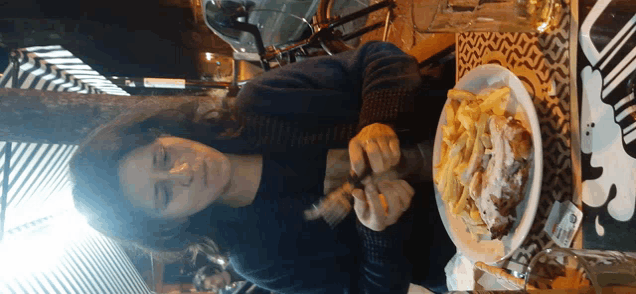 a woman sits at a table with a plate of food on it