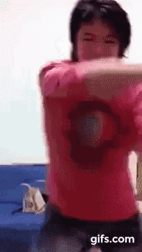 a man in a red shirt is dancing with his arms outstretched