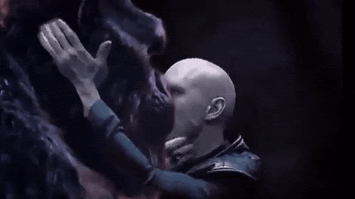 a man is touching a monster 's face in the dark .