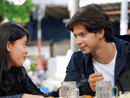 a man and a woman are sitting at a table with glasses of beer