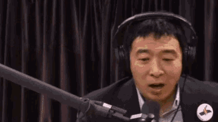 a man wearing headphones is talking into a microphone with the words 100 % bro above him
