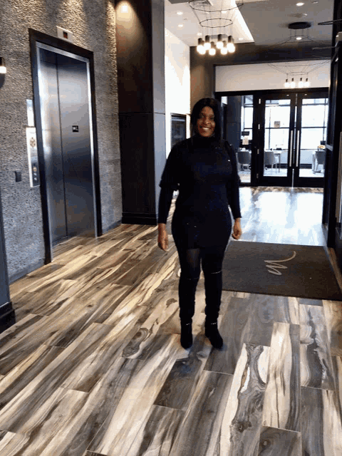 a woman is standing in a hallway with a sign that says m on it