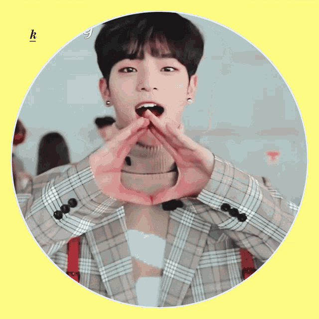 a man in a plaid jacket making a heart shape with his hands with the letter k below him