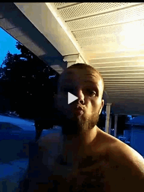 a man without a shirt is standing on a porch
