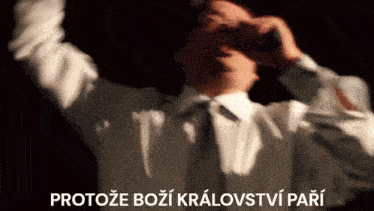 a man in a white shirt and tie holds his hands up in the air with the words protoze bozi kralovstvi pari written above him