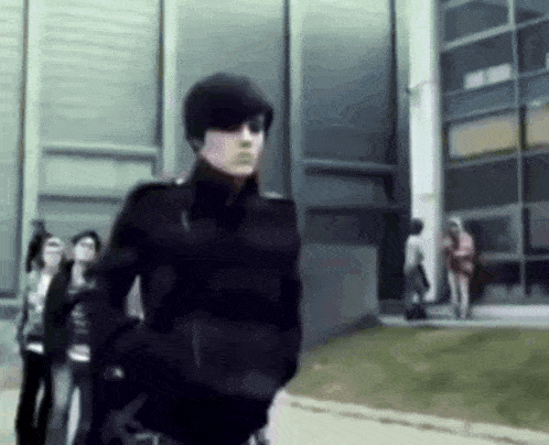a man in a black jacket is walking in front of a building