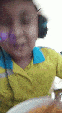 a child wearing headphones and a yellow shirt is smiling
