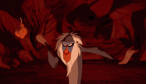 a cartoon monkey is standing next to a lion in a cave and making a funny face .