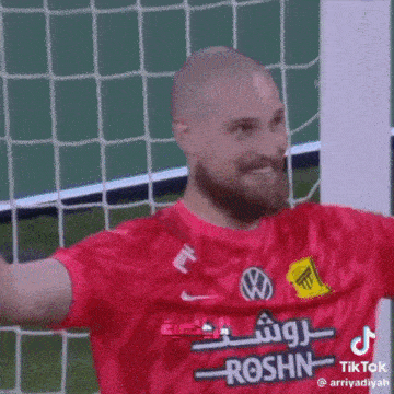 a soccer player wearing a red shirt with roshn written on it