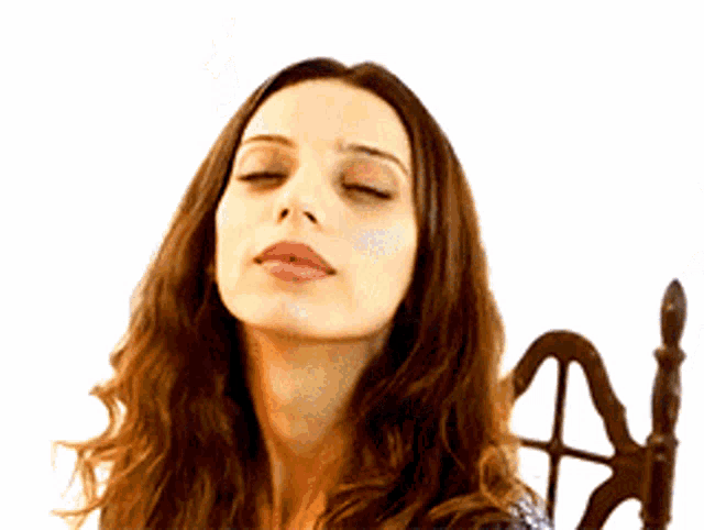 a woman with her eyes closed is sitting on a chair