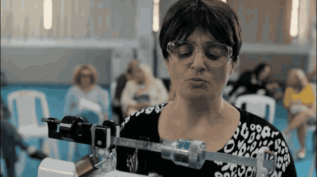 a woman wearing glasses and a leopard print shirt weighs herself on a machine