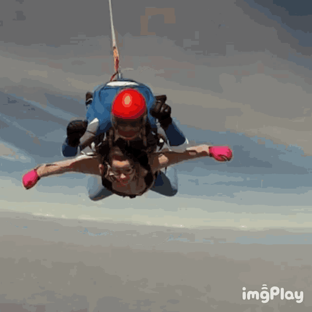 a person in a red helmet is being pulled by a person in a blue jacket and gloves