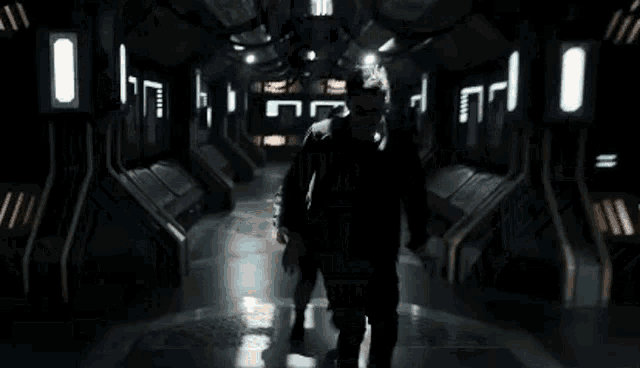 a man is running through a dark hallway in a space ship .