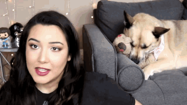 a woman sits on a couch next to a dog wearing a bandana