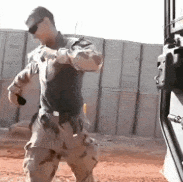 a soldier in a military uniform is dancing in front of a truck .