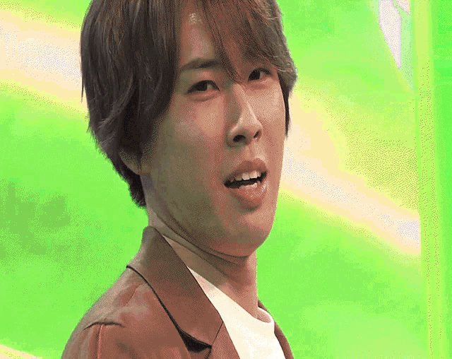 a close up of a man 's face with a green background behind him