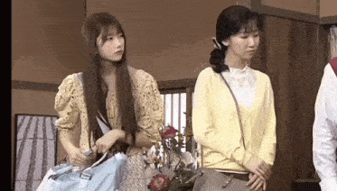 two women standing next to each other in a room .