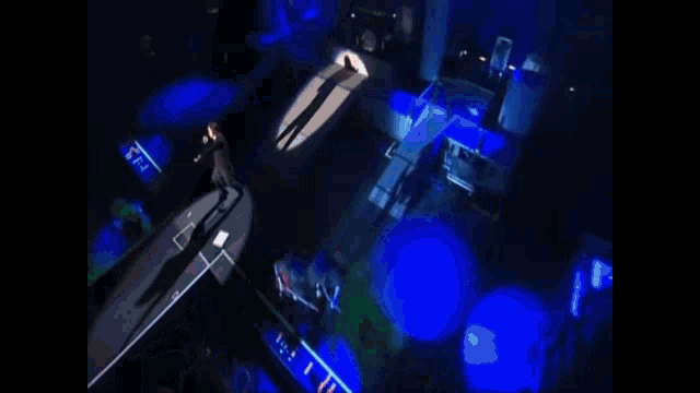 an aerial view of a stage with blue lights and a shadow of a man on it