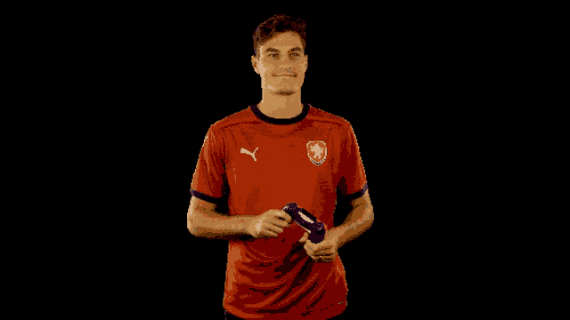 a man in a red puma shirt holds a game controller