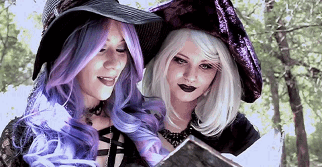 two women dressed as witches are looking at a book together
