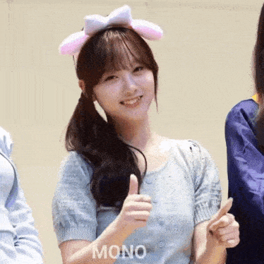 a woman wearing a headband with bunny ears is giving a thumbs up