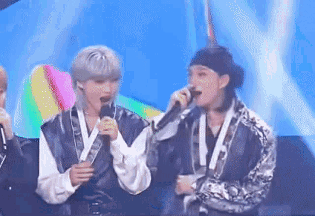 a couple of men are singing into microphones on a stage .
