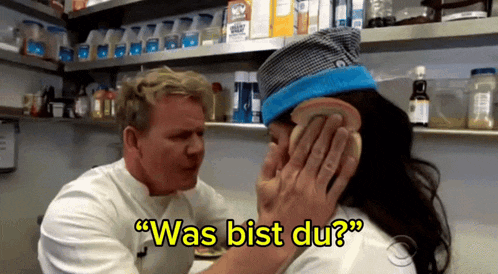 a man holds a piece of bread to a woman 's face and says " was bist du " in yellow letters